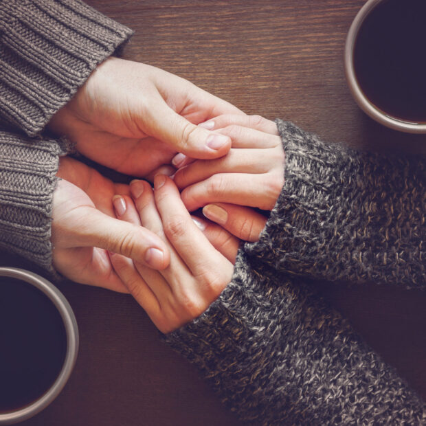 Man holding woman's hands. Young couple enjoying coffee and love