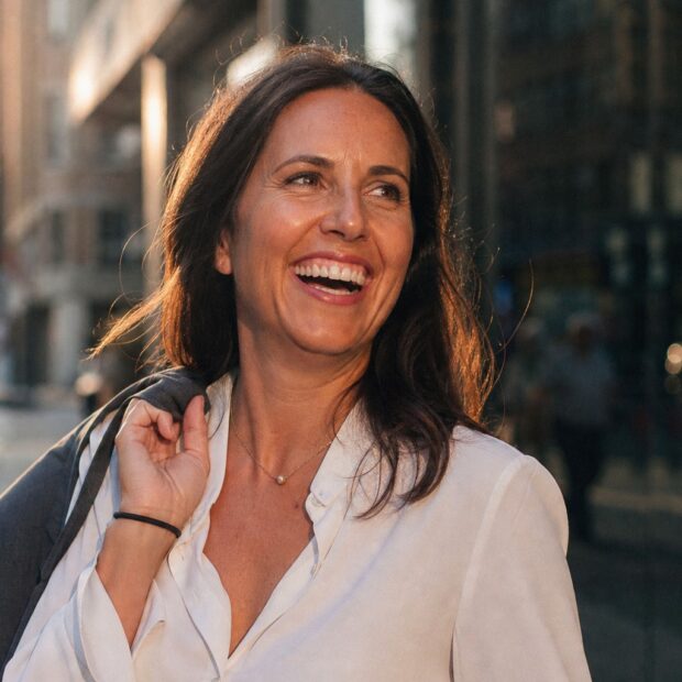 A smiling woman outdoors in warm afternoon light, the positive after of starting depression therapy.